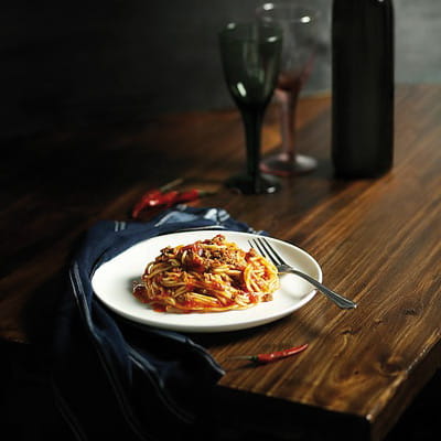 Ein Teller mit Pasta al forno auf einem edlen Holztisch